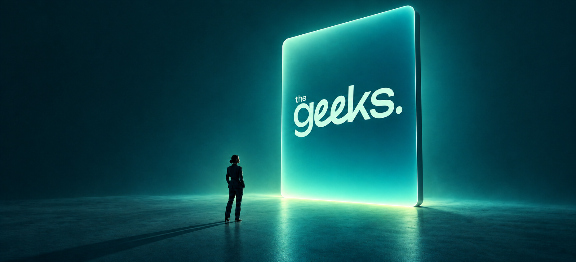 A silhouette facing an illuminated screen displaying The Geeks logo